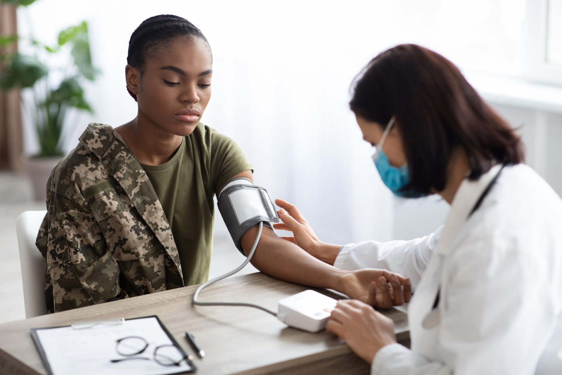 Female soldier having her blood pressure checked by a healthcare provider in a medical office.