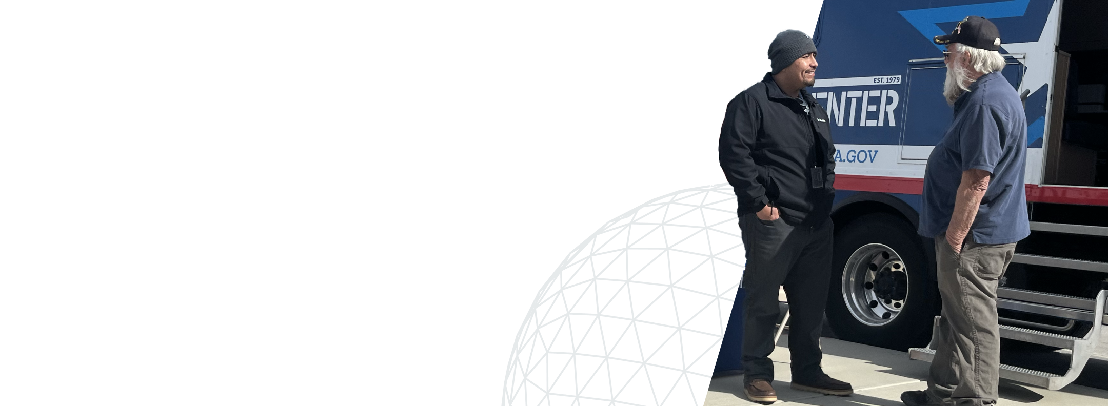 Image of two men talking in front a van