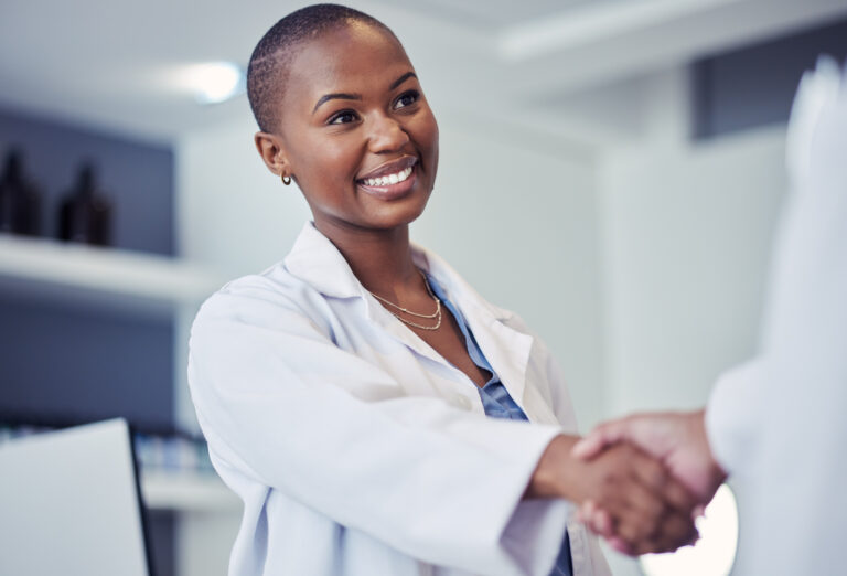 Photo of a woman doctor with a smile, shaking hands with another person