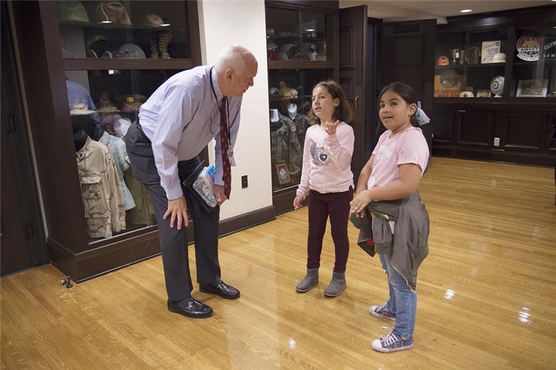 Image of a man leaning over, talking to two young children