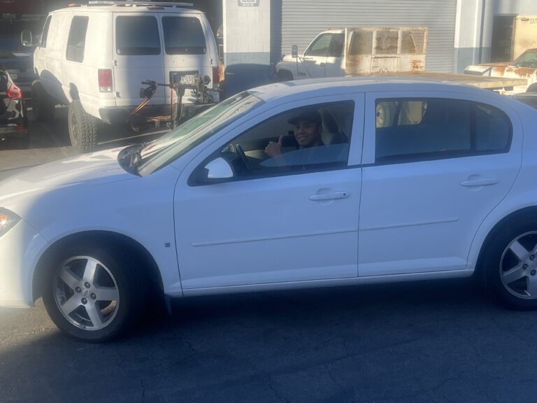 A Veteran smiling and giving a thumbs-up from a white sedan