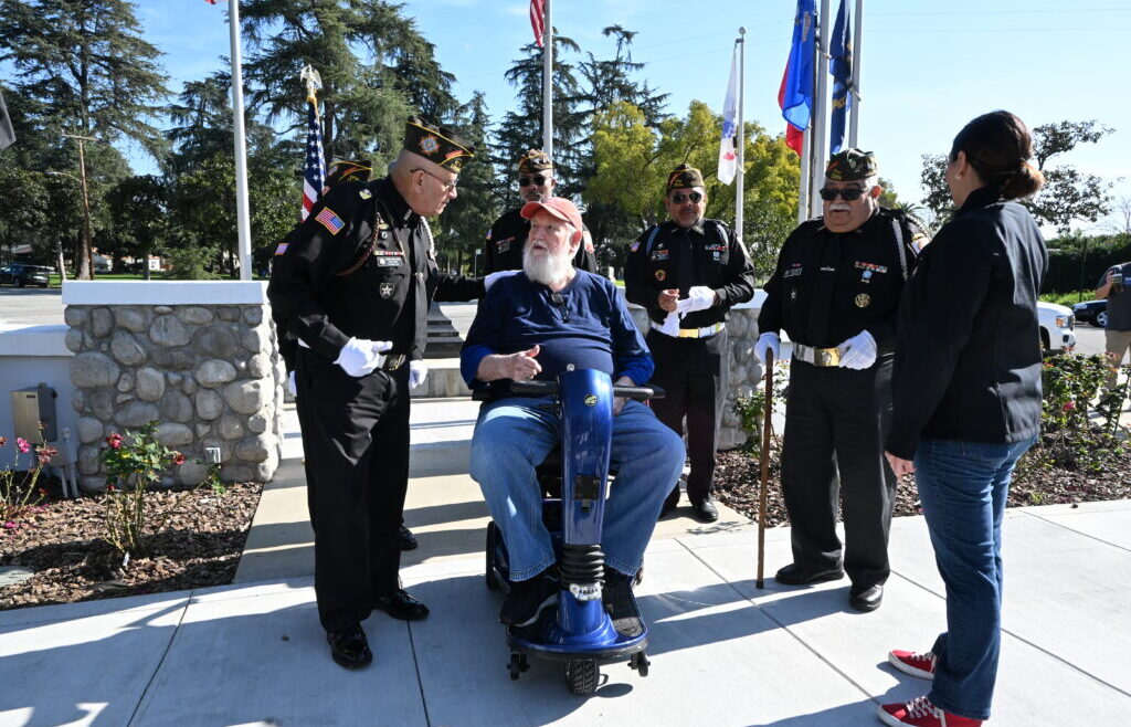 Navy Veteran John &ldquo;Jack&rdquo; McElveen sits on his new mobility scooter during a community presentation at VFW Post 12034 in La Verne, surrounded by VFW members, local leaders, and veteran advocates who gathered to support his independence and wellbeing.