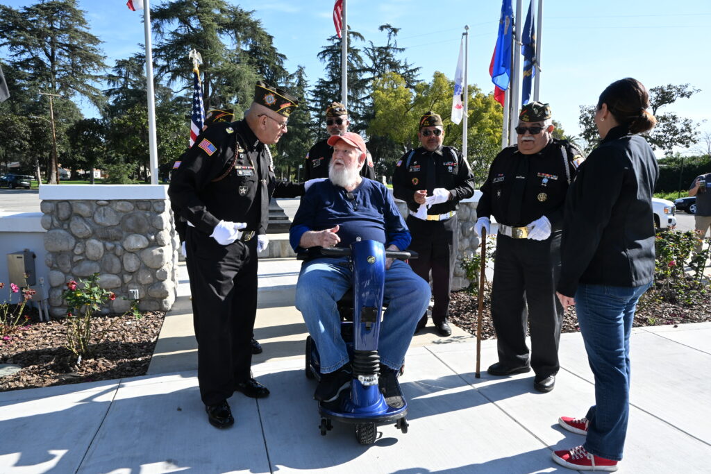 Navy Veteran John &ldquo;Jack&rdquo; McElveen sits on his new mobility scooter during a community presentation at VFW Post 12034 in La Verne, surrounded by VFW members, local leaders, and veteran advocates who gathered to support his independence and wellbeing.