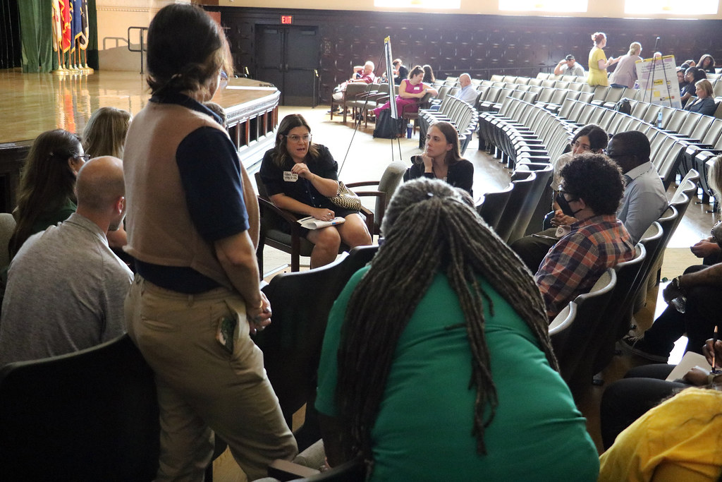 People sitting and standing in an auditorium talking
