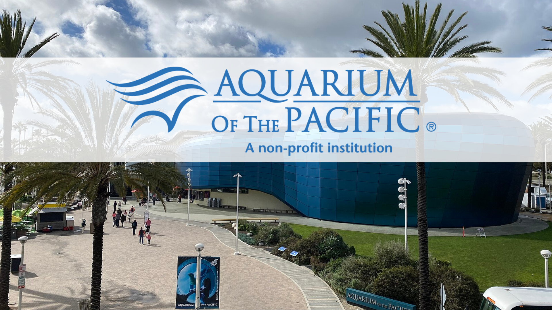 Exterior view of the Aquarium of the Pacific in Long Beach, California, with visitors walking along a palm-lined pathway in front of the blue curved building. The Aquarium of the Pacific logo and tagline ‘A non-profit institution’ are displayed across the image.