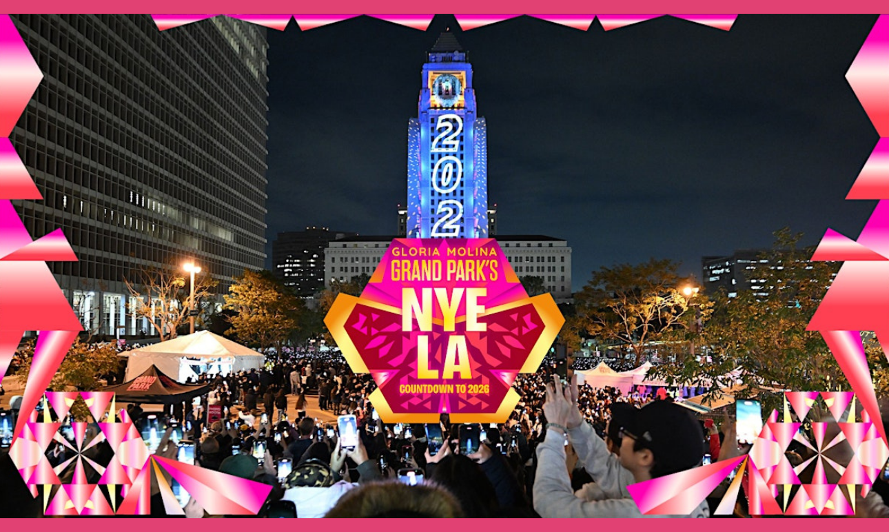 Crowd gathers at Gloria Molina Grand Park at night as Los Angeles City Hall displays a “2026” countdown projection, with NYE LA branding overlaid in the foreground.